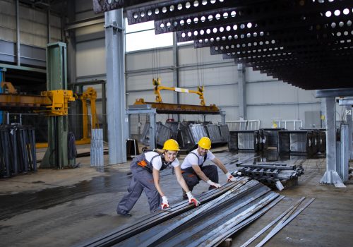 Factory workers handling metal parts together.