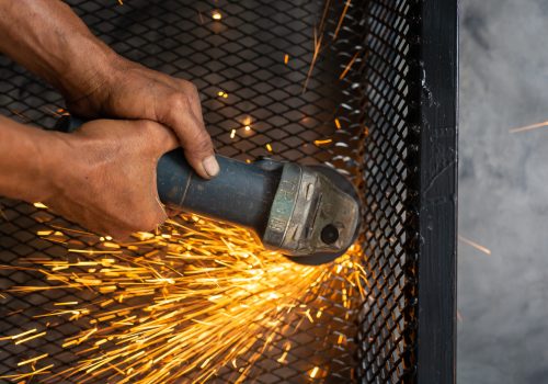 Male workers cut and weld metal with spark.